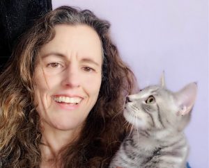 Professional headshot of Dilara Goksel Parry holding a grey tabby cat.